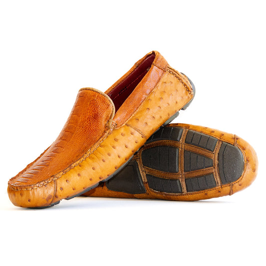 A pair of Alba Brandy luxury moccasin loafers by Marco Di Milano, crafted from genuine tan ostrich leather with a distinctive textured surface and black rubber soles—one shoe displayed upright and the other shown lying on its side.
