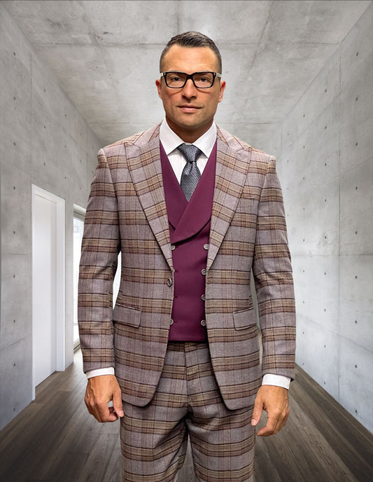 A man wearing glasses and a Statement Clothing STATEMENT CLOTHING | AMICCI-BURGUNDY modern fit plaid peak lapel suit with a maroon vest stands in a sleek concrete hallway with wooden floors.