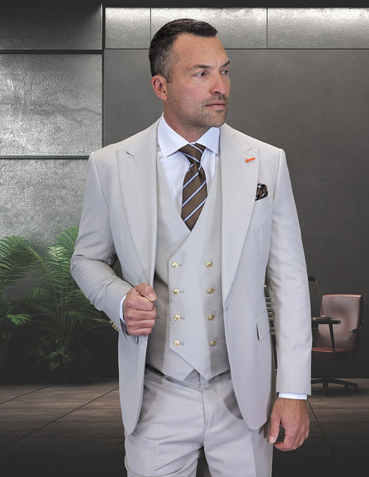 A man in the STATEMENT CLOTHING | AMIRI-ASH modern fit Italian wool three-piece light grey suit and striped tie stands in a modern office with plants and an office chair, representing Statement Clothing.