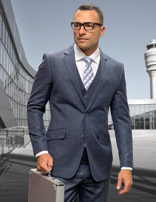 A man in the STATEMENT CLOTHING | ANGEL-3-CHARCOAL modern fit Italian wool suit by Statement Clothing, wearing glasses and flat front pants, holds a silver briefcase outside an airport terminal with a control tower in the background.