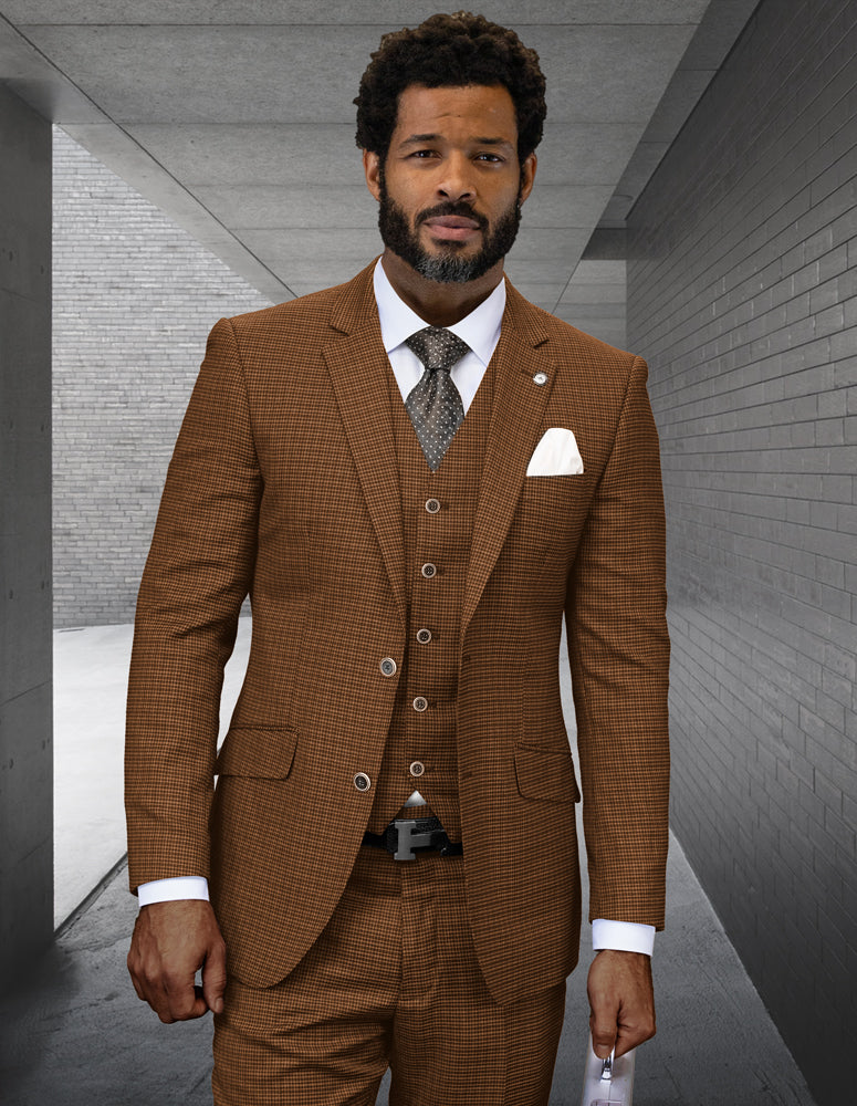 A man in a STATEMENT CLOTHING | ANGEL-4-COPPER modern fit Italian wool three-piece suit by Statement Clothing, with a white shirt and patterned tie, stands in a gray concrete hallway holding a piece of paper.