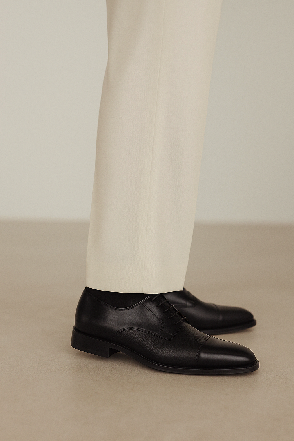 The BELVEDERE Alexander is a black men's dress shoe made of genuine Italian deerskin and calf, featuring a cap toe, lace-up closure, and low heel. Handcrafted in Brazil, shown in side profile on a white background.