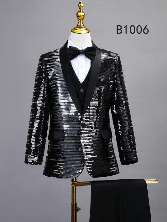 The BOY SUIT 5-PC SET B1006 by Unique Design Menswear features a black sequin tuxedo jacket, shawl lapel, bow tie, vest, and matching trousers—an elegant boys’ formal wear ensemble displayed on a labeled mannequin.