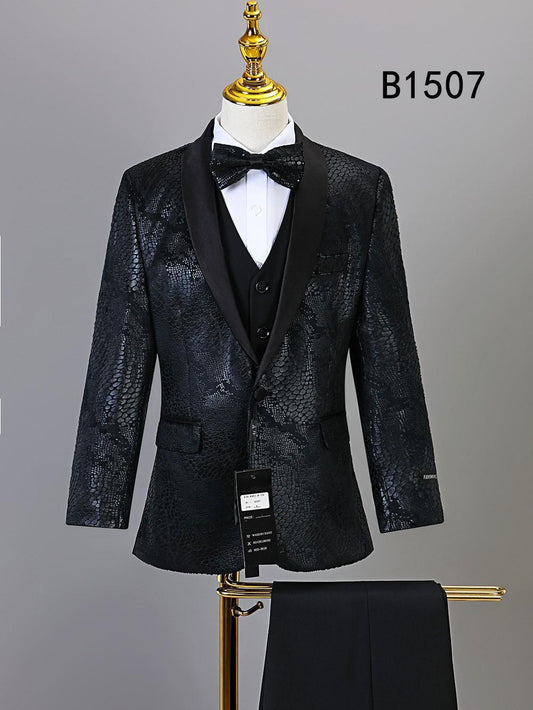 The BOY SUIT 5-PC SET B1507 by Unique Design Menswear features a black textured formal outfit with satin lapels, bow tie, vest, and pants displayed on a gold-stand mannequin—perfect for special occasions. Label tags and code B1507 visible.