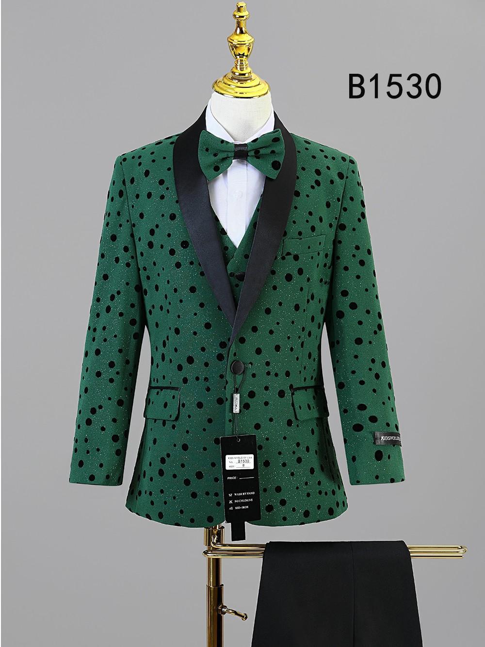 The BOY SUIT 5-PC SET B1530 by Unique Design Menswear includes a green jacket with black polka dots and lapels, matching bow tie and vest, and black pants. Shown on a mannequin, it's an ideal formal wear choice for boys.