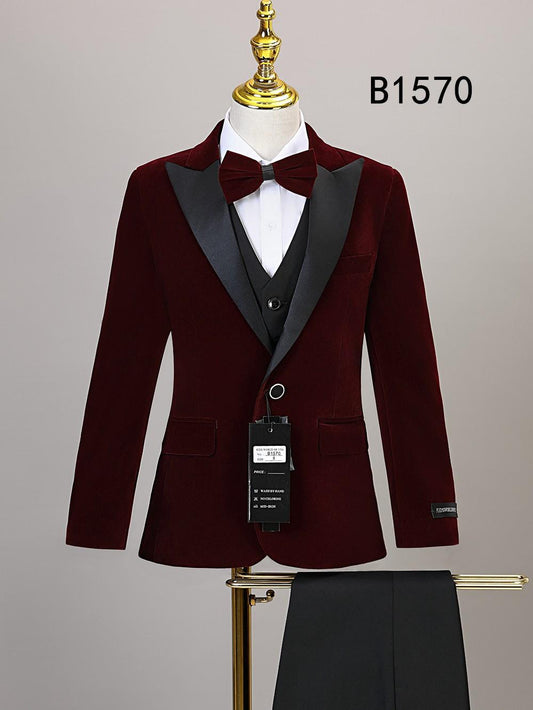 The BOY SUIT 5-PC SET B1570 by Unique Design Menswear features a burgundy velvet jacket with black satin lapels, bow tie, vest, and pants—perfect for boys' formal wear. Displayed on a mannequin.