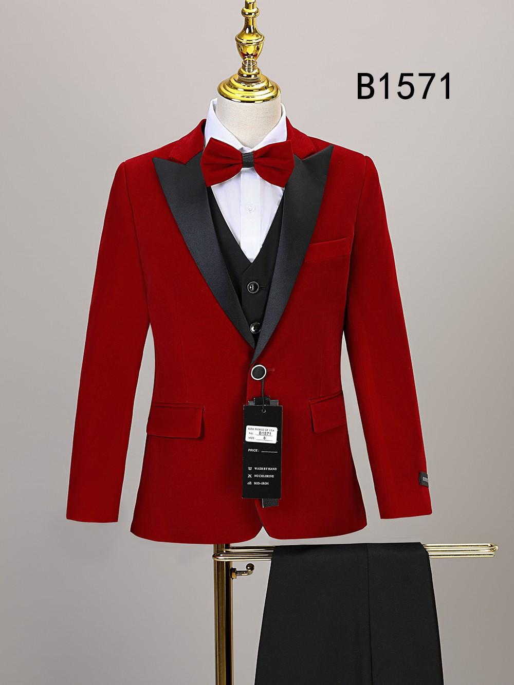 The Unique Design Menswear BOY SUIT 5-PC SET B1571 for boys features a red jacket with black lapels, matching bow tie, black vest, white shirt, and black pants. Displayed on a stand with model number B1571 in the background.