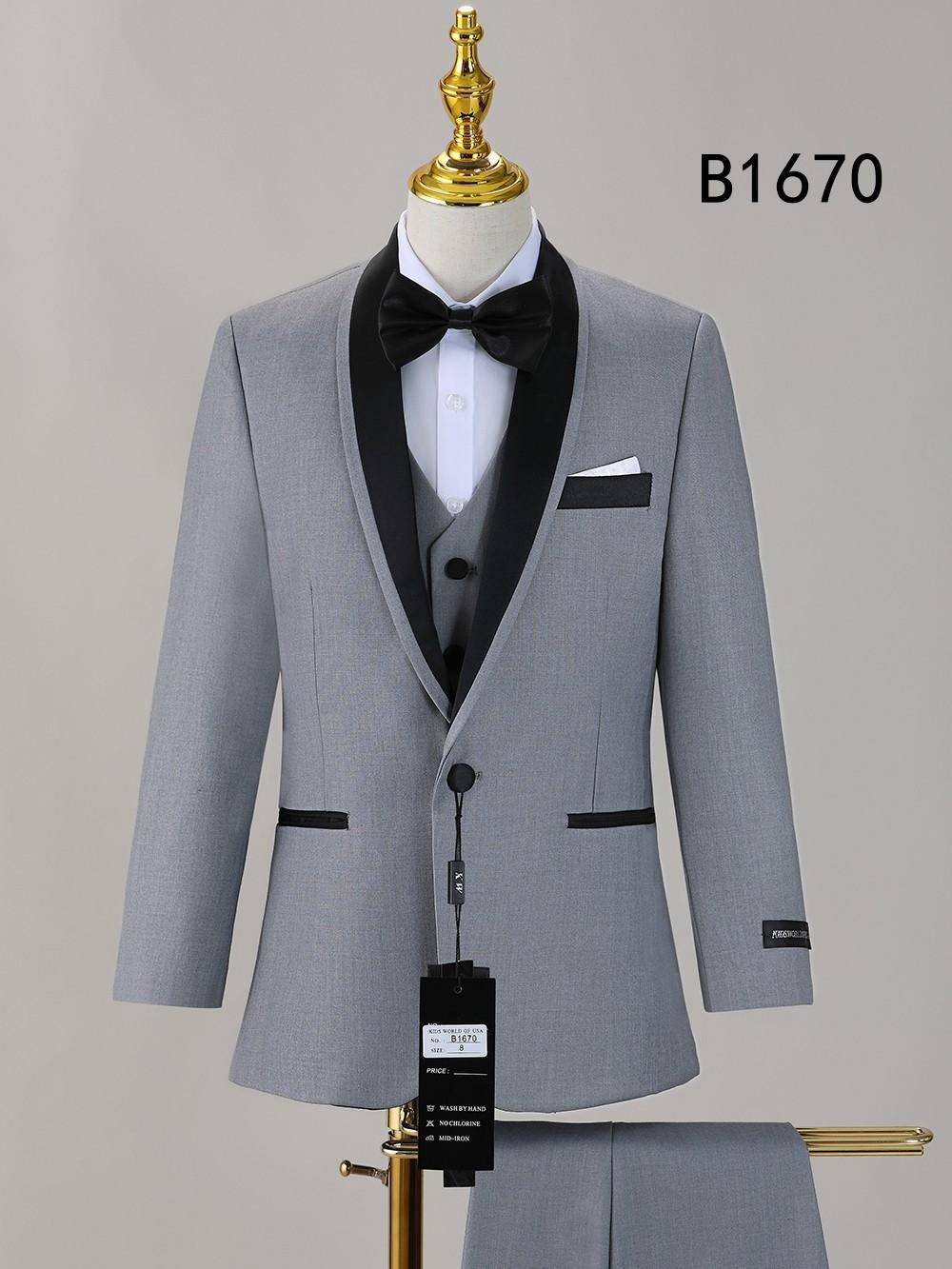 The BOY SUIT 5-PC SET B1670 by Unique Design Menswear features a light gray tuxedo with black lapels, bow tie, and accents, plus a white shirt. Displayed on a mannequin with pants draped below. "B1670" appears in the upper right corner.
