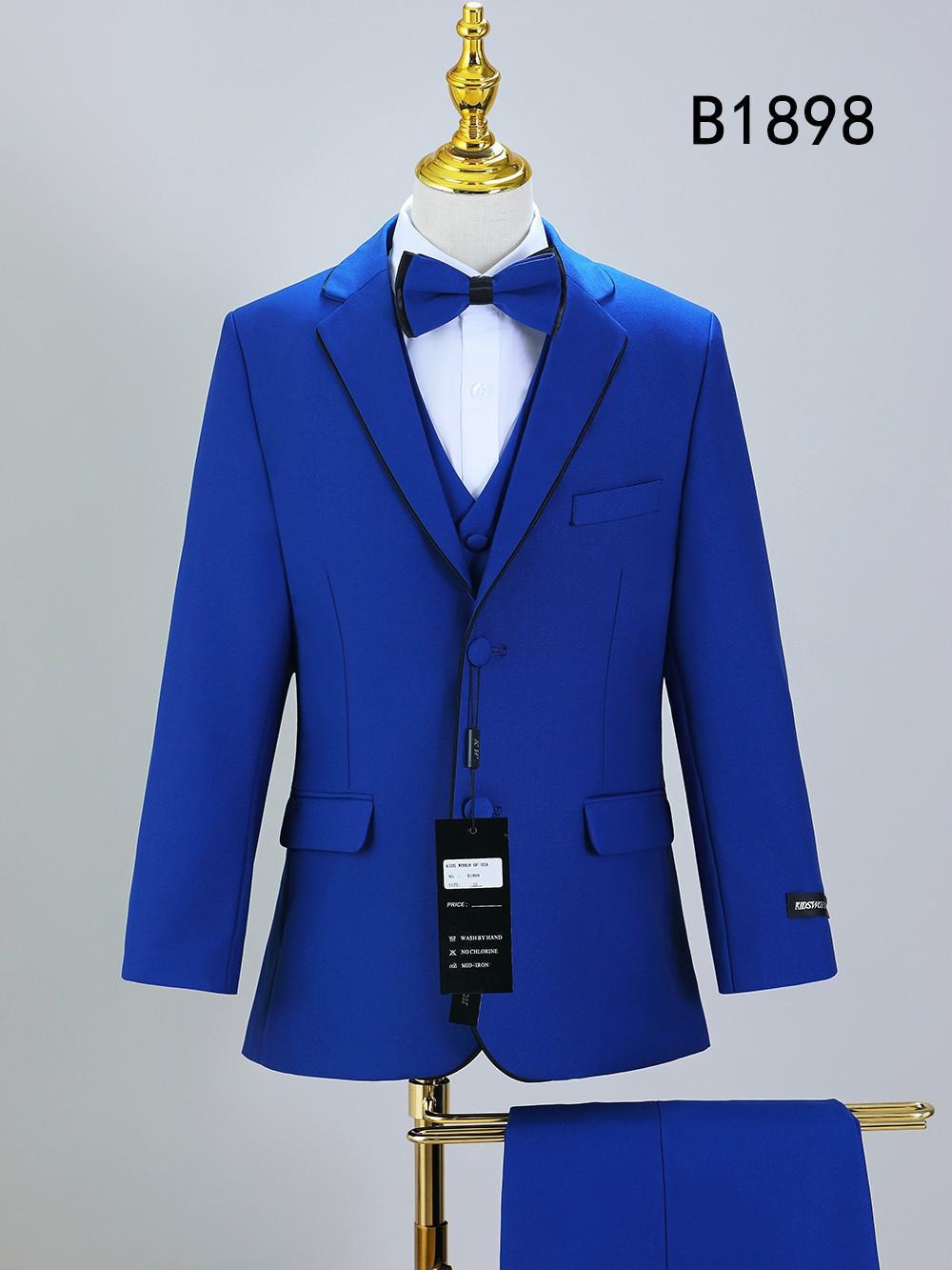 The Unique Design Menswear BOY SUIT 5-PC SET B1898, in royal blue with black trim, is displayed on a mannequin. The set includes a bow tie, vest, and pants with tags attached. Model number B1898 is shown at the top right.