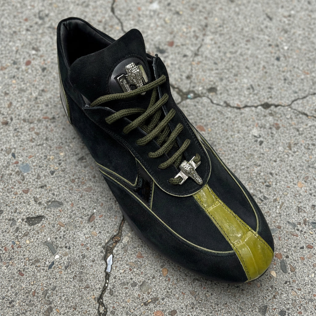 The Mauri 8464 Black/Olive sneaker (Size 8.5 Only) features suede with a glossy green stripe, elegantly placed on a wooden floor. FINAL SALE - NO EXCHANGE, NO RETURN.