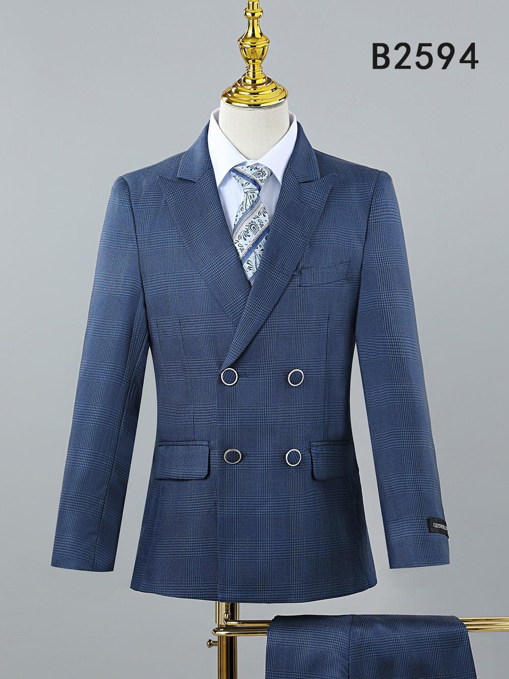 The Unique Design Menswear BOY SUIT 5-PC SET B2594 is a double-breasted blue plaid boy's suit with silver buttons, white dress shirt, and patterned tie, shown on a mannequin—perfect for boys' formal occasions. "B2594" is featured in the top right corner.
