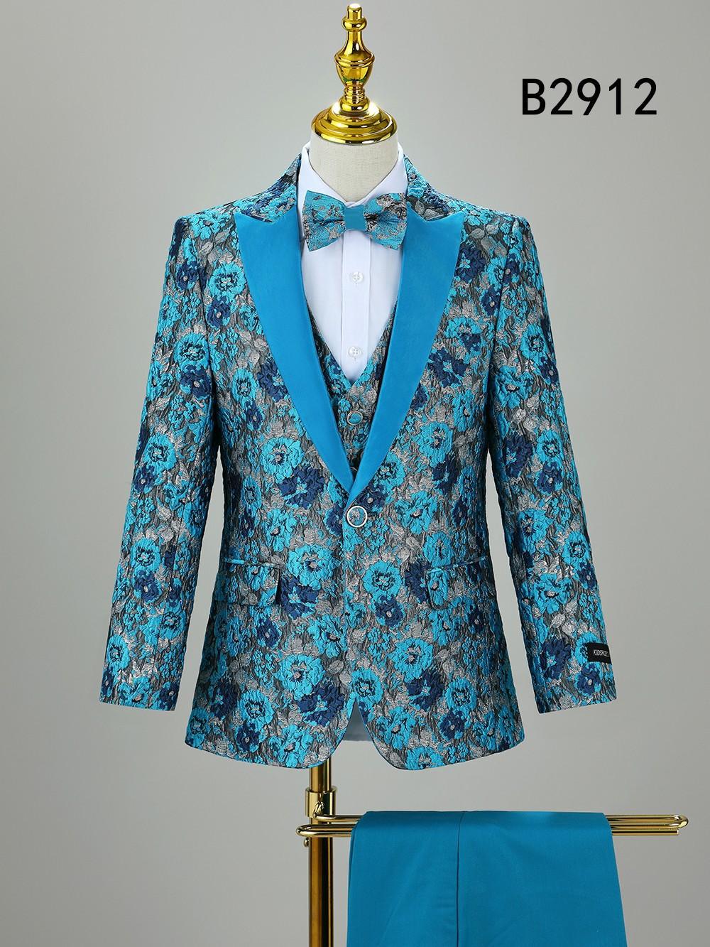 The BOY SUIT 5-PC SET B2912 by Unique Design Menswear features a blue floral jacket, matching vest, bow tie, and solid blue dress pants. Displayed on a stand with the label "B2912" in the top right—ideal formal wear for boys.