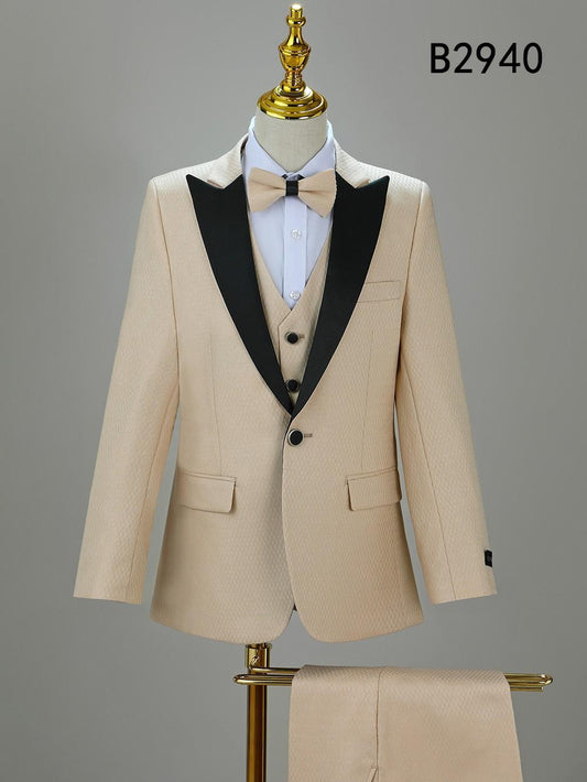 The BOY SUIT 5-PC SET B2940 by Unique Design Menswear features a beige suit with black lapels, white shirt, and beige bow tie, shown on a mannequin. Ideal boys’ formal wear. Product code B2940 displayed at top right.
