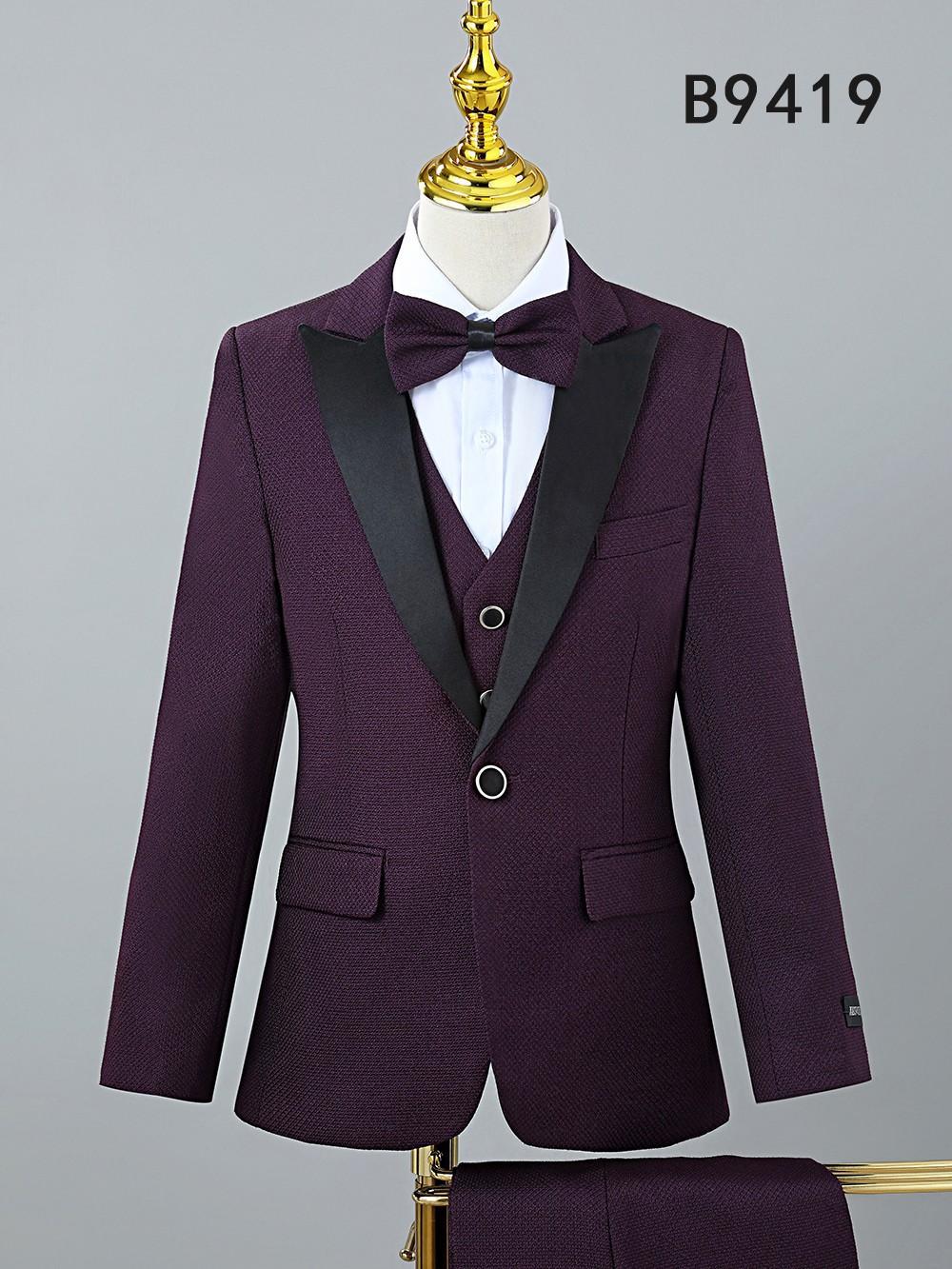The Unique Design Menswear BOY SUIT 5-PC SET B9419 features a purple tuxedo with black lapels, white dress shirt, and matching bow tie, displayed on a mannequin. The code "B9419" appears in the top right corner.