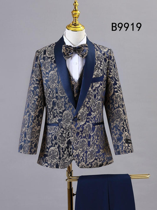 The BOY SUIT 5-PC SET B9919 by Unique Design Menswear features a navy blue and gold paisley pattern with vest and bow tie, shown on a mannequin with navy formal pants—a standout in boys' formal wear.
