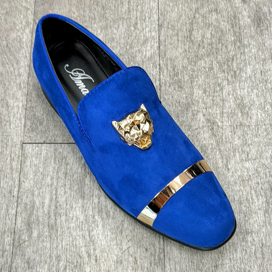 Crafted in Italy, the Exclusive Formal Dress Shoe Blue EARL by UNIQUE DESIGN MENSWEAR features a luxurious genuine suede leather loafer in blue, adorned with a gold-colored lion's head detail and an elegant gold band across the toe, showcased on a gray textured floor.