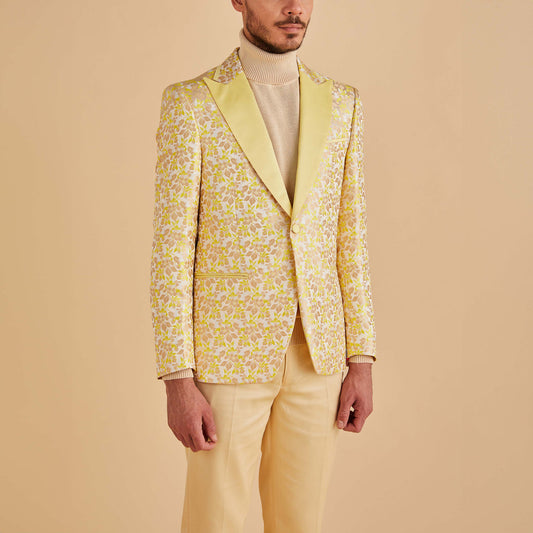 A man wears the Inserch Floral Jacquard Blazer BL203-16 Yellow by Inserch with a beige turtleneck and matching yellow trousers against a beige background.