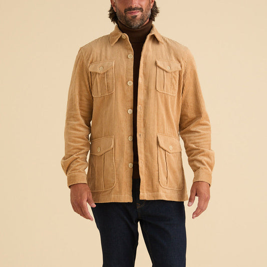 A man wears the Inserch Corduroy 4-Pkt Blazer BL267-09 Khaki by Inserch, made from 100% cotton, over a brown turtleneck and dark jeans, standing against a plain beige background.