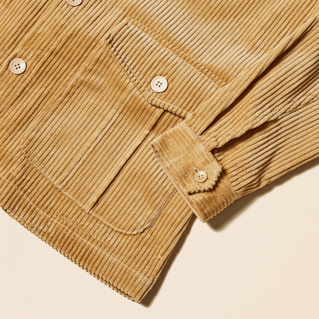 A man wears the Inserch Corduroy 4-Pkt Blazer BL267-09 Khaki by Inserch, made from 100% cotton, over a brown turtleneck and dark jeans, standing against a plain beige background.