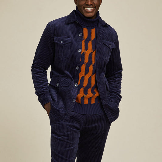 A person wearing the Inserch Corduroy 4-Pkt Blazer BL267-11 Navy by Inserch over an orange and navy patterned sweater, standing with hands in pockets and smiling.