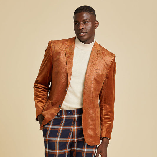 A man in an Inserch Suede Snake Skin Blazer BL268-104 Cognac over a cream turtleneck and blue, orange, and white plaid pants stands against a beige background.