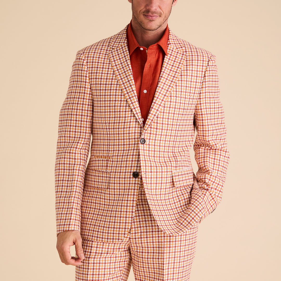 A person confidently stands against a plain background, adorned in the Inserch Houndstooth Linen Blazer BL279-00035 Rust and a vibrant red shirt.