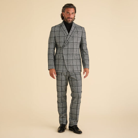A man stands against a beige background wearing the Inserch DB Glenn Check Blazer BL504-41 Black/White, paired with a black turtleneck and black shoes.