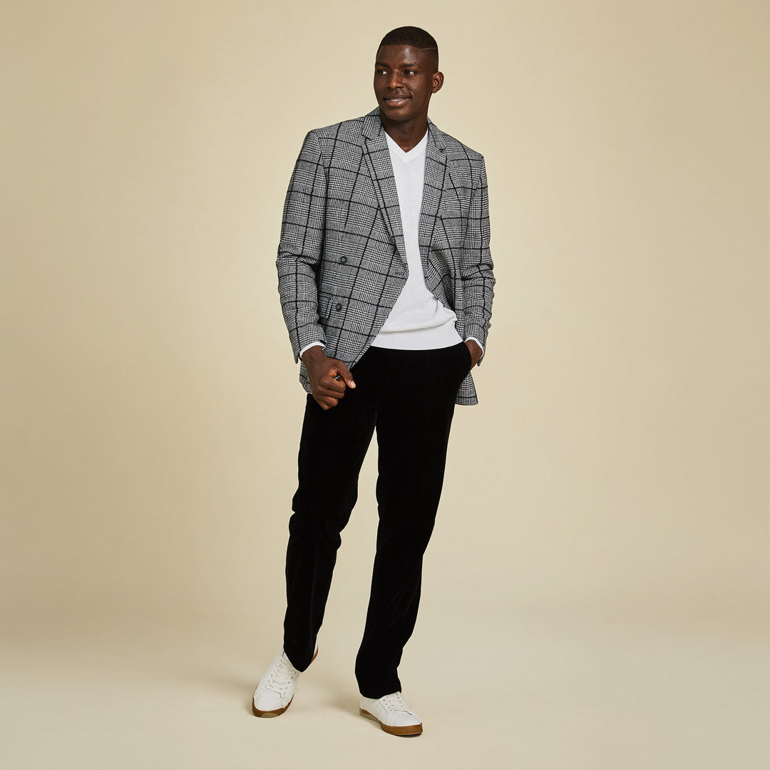 A man stands against a beige background wearing the Inserch DB Glenn Check Blazer BL504-41 Black/White, paired with a black turtleneck and black shoes.