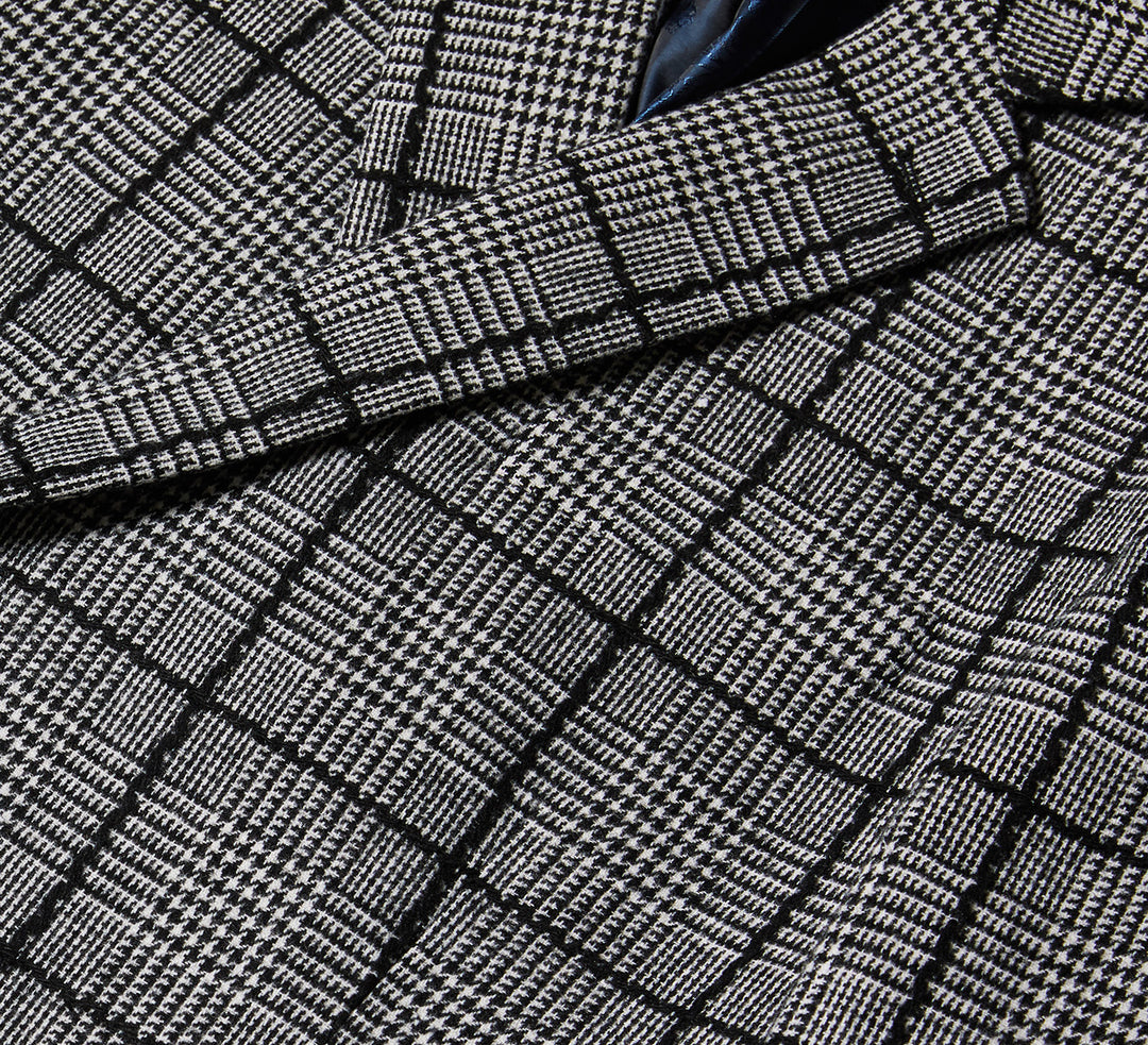 A man stands against a beige background wearing the Inserch DB Glenn Check Blazer BL504-41 Black/White, paired with a black turtleneck and black shoes.