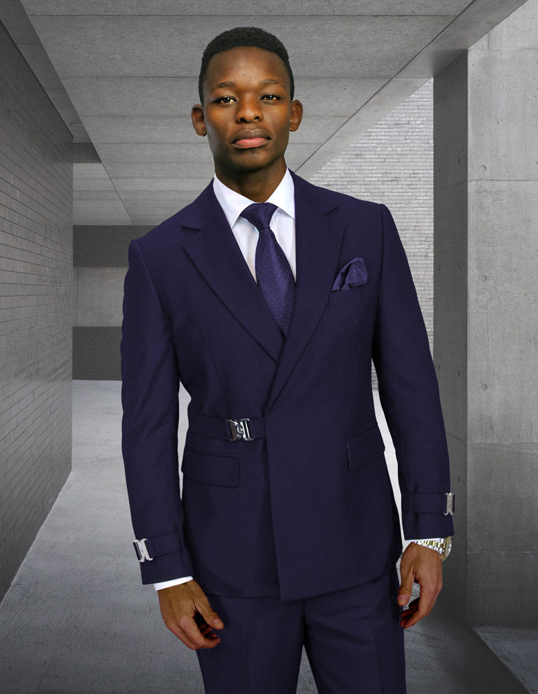 A man stands in a modern concrete corridor wearing the STATEMENT CLOTHING | BOLANZO-NAVY suit by Statement Clothing, featuring a modern fit Italian wool design with a white shirt and purple tie.