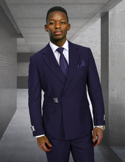 A man stands in a modern concrete corridor wearing the STATEMENT CLOTHING | BOLANZO-NAVY suit by Statement Clothing, featuring a modern fit Italian wool design with a white shirt and purple tie.