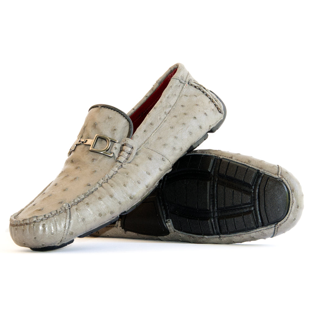 A pair of Bolonia Gray luxury moccasin loafers by Marco Di Milano, featuring a light gray textured surface, metal buckle detail, and black rubber soles, displayed against a white background.