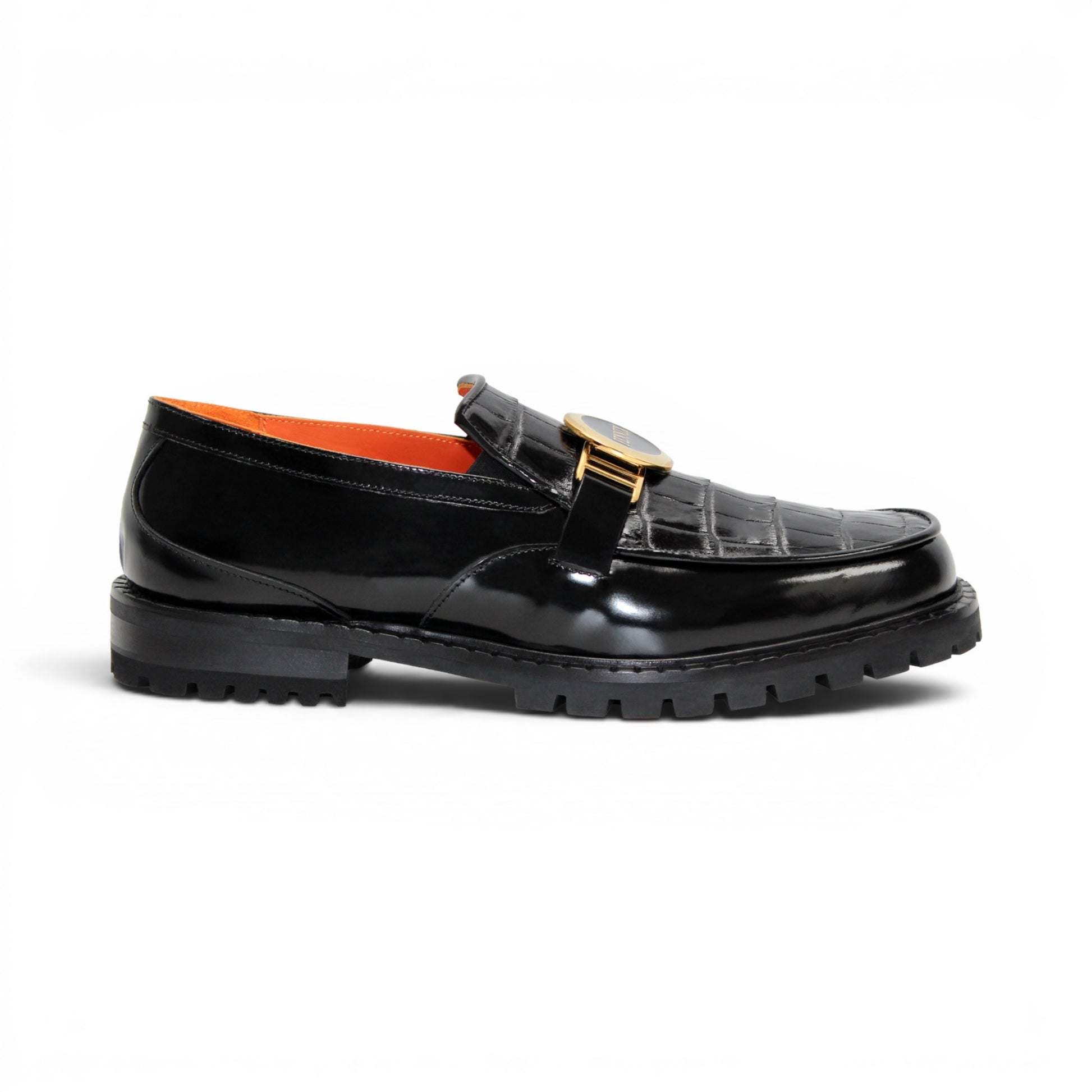 The Fennix Brant Black by Fennix of Italy is an Italian-crafted black patent loafer featuring a textured pattern, thick ridged sole, gold hardware buckle detail, and an orange inner lining, displayed in profile against a white background.