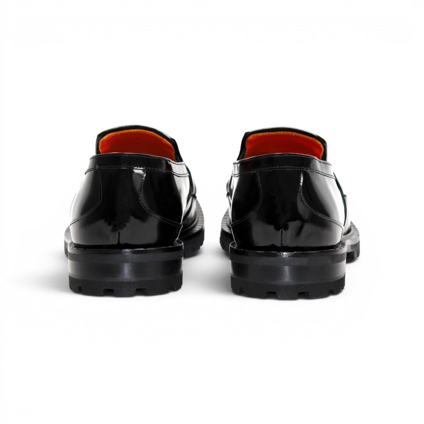 The Fennix Brant Black by Fennix of Italy is an Italian-crafted black patent loafer featuring a textured pattern, thick ridged sole, gold hardware buckle detail, and an orange inner lining, displayed in profile against a white background.