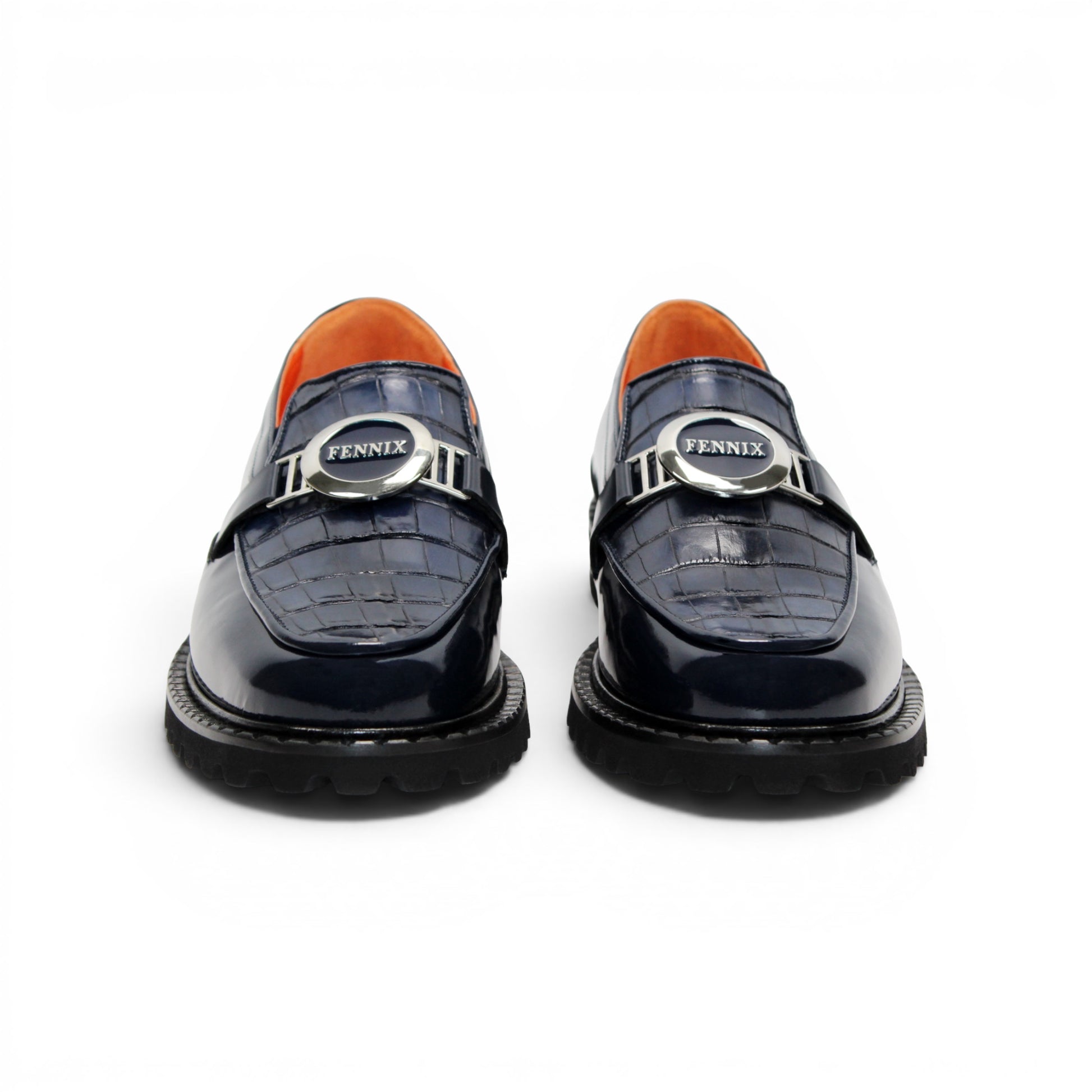 Introducing the Fennix Brant Navy from Fennix of Italy—a sleek navy blue loafer featuring a chunky black sole, vibrant orange inner lining, and a silver buckle accent across the upper strap. Expertly crafted in Italy, this shoe blends contemporary flair with classic elegance.
