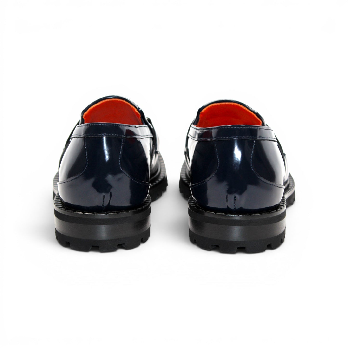Introducing the Fennix Brant Navy from Fennix of Italy—a sleek navy blue loafer featuring a chunky black sole, vibrant orange inner lining, and a silver buckle accent across the upper strap. Expertly crafted in Italy, this shoe blends contemporary flair with classic elegance.