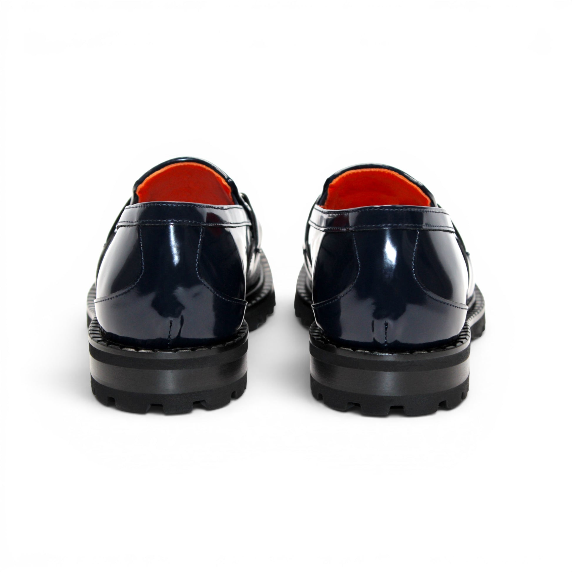 Introducing the Fennix Brant Navy from Fennix of Italy—a sleek navy blue loafer featuring a chunky black sole, vibrant orange inner lining, and a silver buckle accent across the upper strap. Expertly crafted in Italy, this shoe blends contemporary flair with classic elegance.