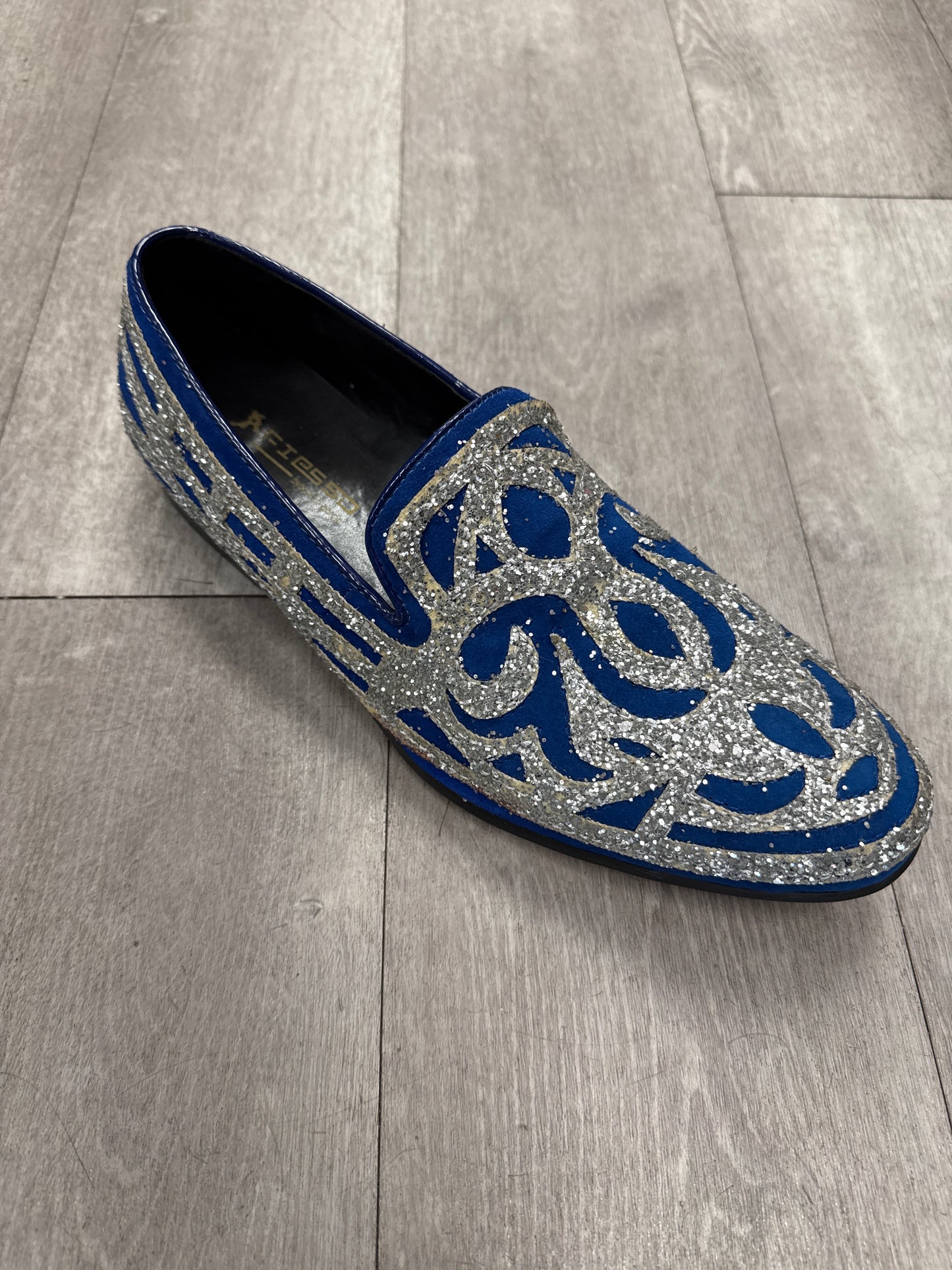 Fiesso Shoe 100, size 8 only, features silver glitter and blue swirl patterns. Displayed on a gray wooden floor. FINAL SALE—NO EXCHANGE, NO RETURN.