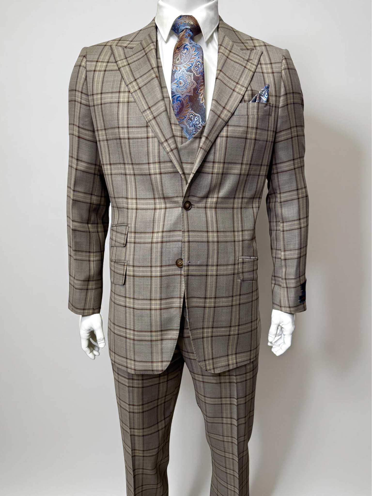 A man with gray hair and beard wears a brown plaid Tiglio Luxe Prosecco Modern Fit suit and vest, paired with a white shirt and patterned tie, standing against a plain light background.