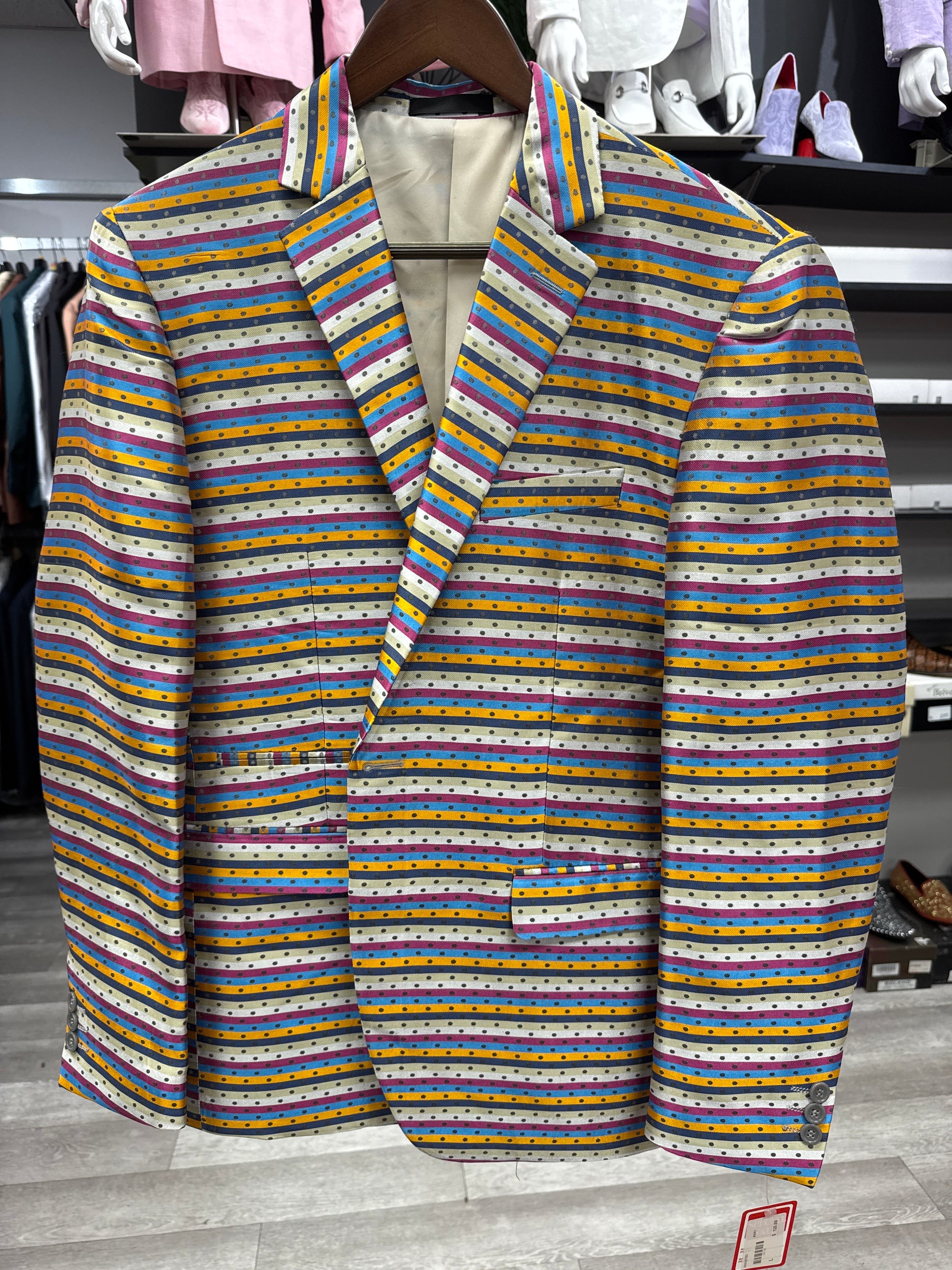 The EJ SAMUEL JACKET 23 CLEARANCE is a blazer featuring horizontal multicolored stripes and small polka dots, shown on a hanger in a clothing store. Please note: this item is final sale—no exchanges or returns.