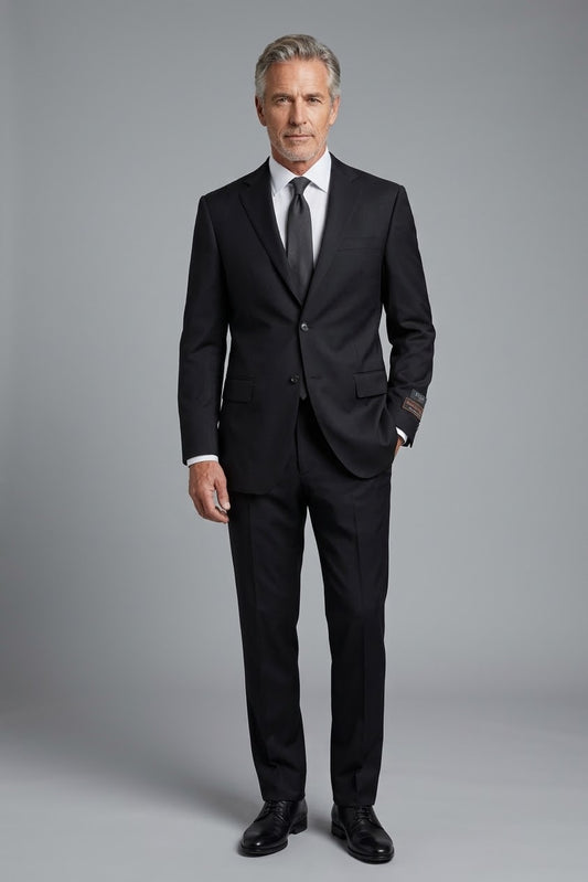 Displayed elegantly on a mannequin, the Tiglio Luxe Novello Modern Fit Black TIG1001 suit by Unique Design Menswear is made from Italian wool and paired with a white dress shirt and dark tie. This ensemble perfectly captures refined elegance with its modern European fit.