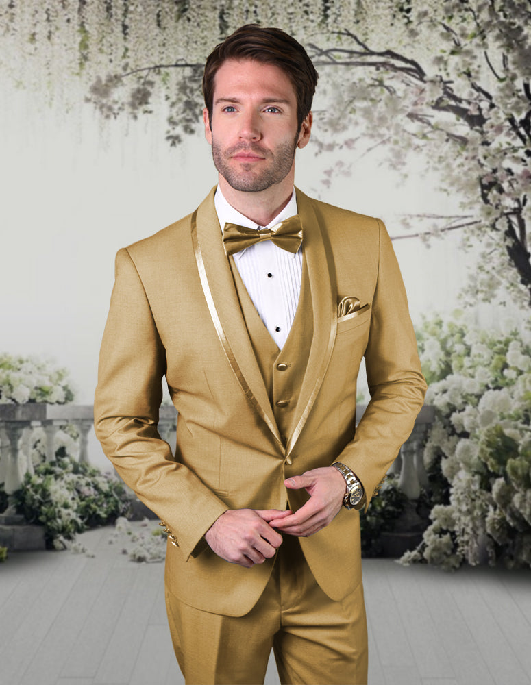 A man wears the STATEMENT CLOTHING | CAESAR-CHAMPAGNE tuxedo from Statement Clothing, featuring a tailored gold fit and champagne bow tie, as he stands before a floral garden-themed backdrop.