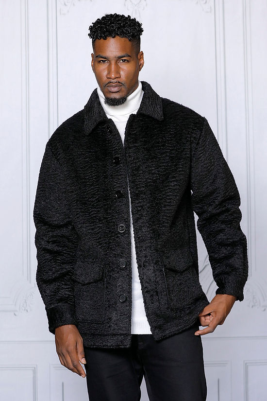 A man in a MANZINI CANADA Black Short Ripple Faux Fur Button Coat by Insomnia, tailored in regular fit, over a white turtleneck against a light gray backdrop.