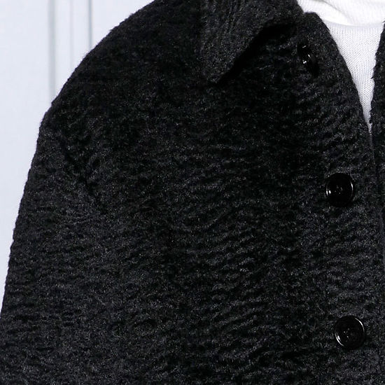 A man in a MANZINI CANADA Black Short Ripple Faux Fur Button Coat by Insomnia, tailored in regular fit, over a white turtleneck against a light gray backdrop.
