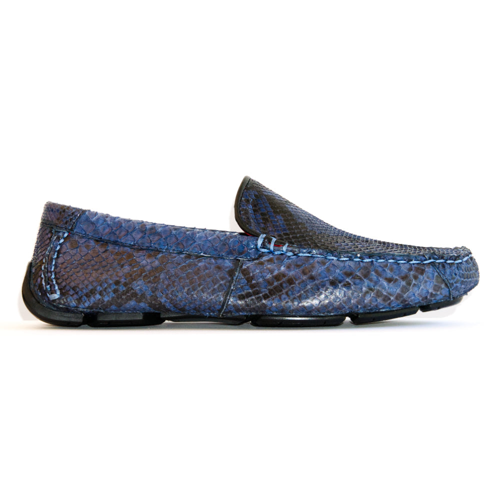 A pair of Capri Blue Jeans loafers by Marco Di Milano, crafted with a striking blue snakeskin texture; one shoe stands upright while the other lies on its side to reveal the black rubber sole—an elegant display of handcrafted luxury for those seeking exquisite exotic footwear.
