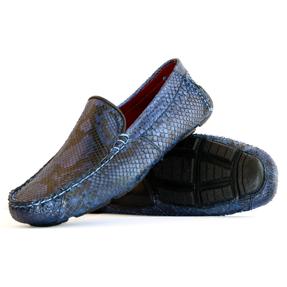 A pair of Capri Blue Jeans loafers by Marco Di Milano, crafted with a striking blue snakeskin texture; one shoe stands upright while the other lies on its side to reveal the black rubber sole—an elegant display of handcrafted luxury for those seeking exquisite exotic footwear.