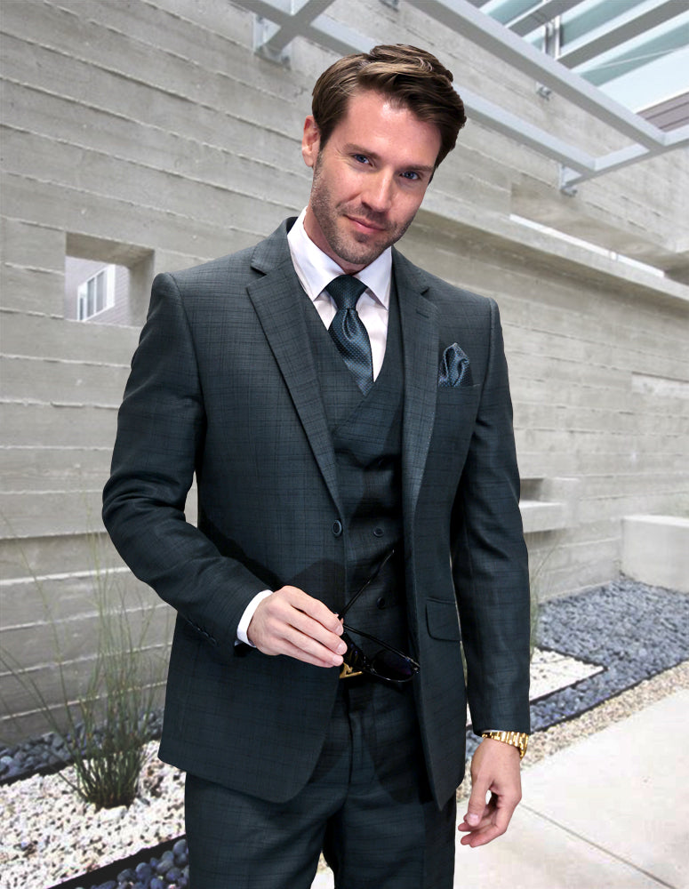 A man in a modern fit STATEMENT CLOTHING | CARNELI-HUNTER charcoal suit by Statement Clothing stands outdoors against a concrete wall, holding sunglasses and looking at the camera.