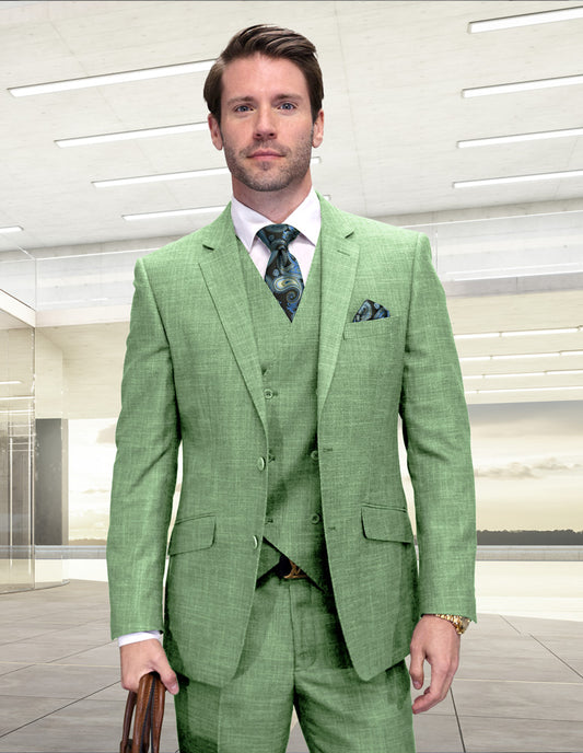 A man in a STATEMENT CLOTHING | CARNELI-SAGE modern fit 3-piece suit by Statement Clothing, with matching vest and patterned tie, stands indoors holding a brown briefcase.