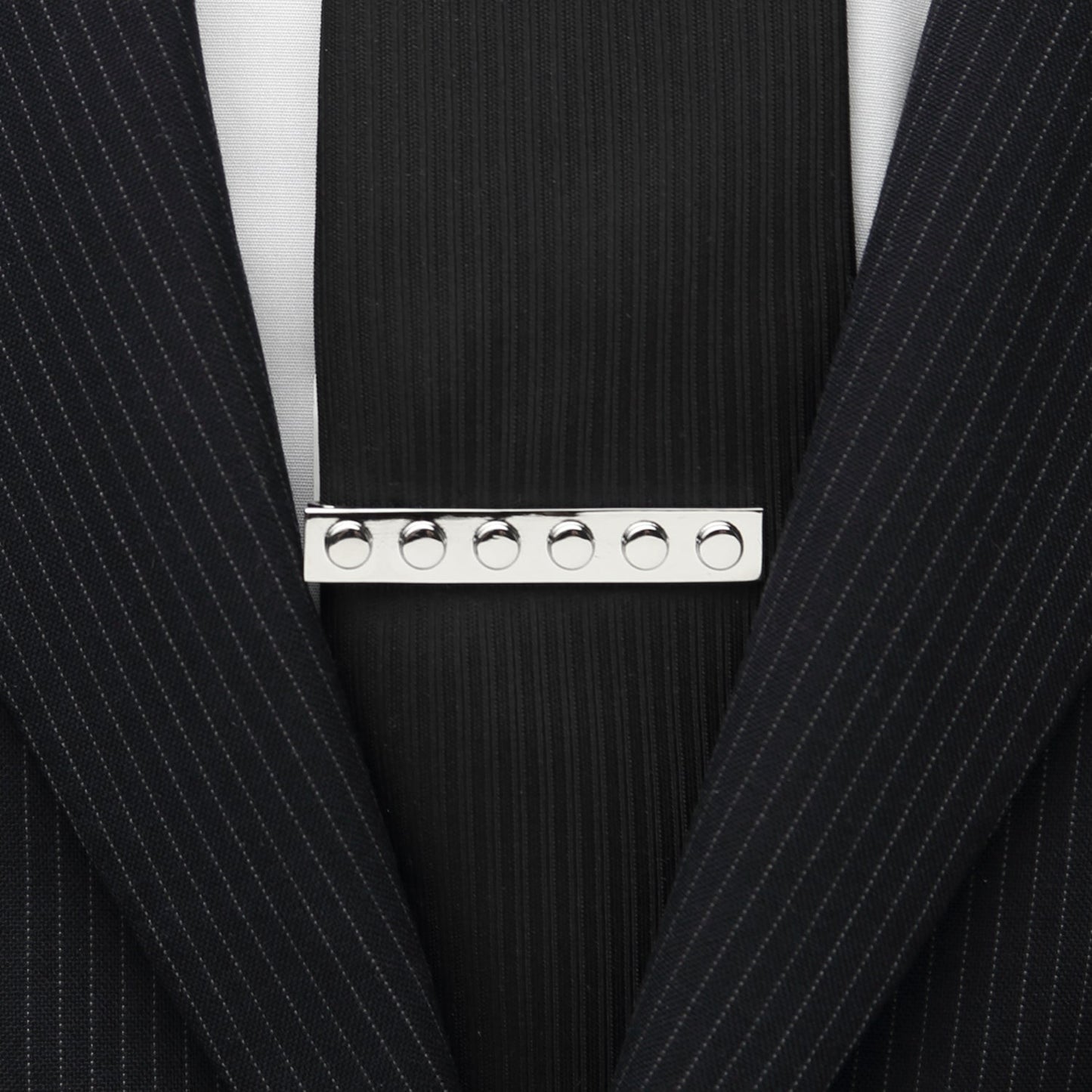 The Silver Building Block Tie Bar by Cufflinks.com features six raised circular studs, displayed against a white background—a must-have accessory for those who dress for success.