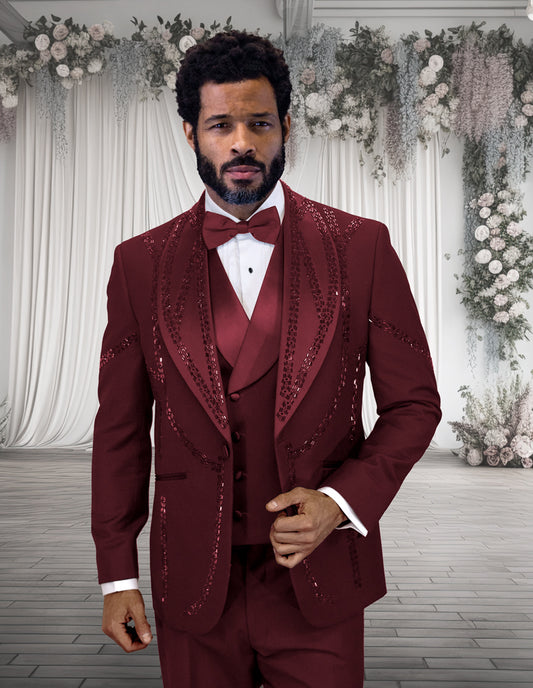 A man in the STATEMENT CLOTHING | CHIC-BURGUNDY modern fit tuxedo by Statement Clothing stands in front of a white floral and drapery wedding backdrop.